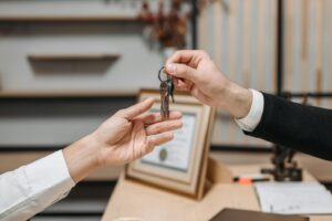 Vue détaillée des mains échangeant des clés dans un environnement de bureau professionnel, symbolisant des transactions immobilières ou commerciales.