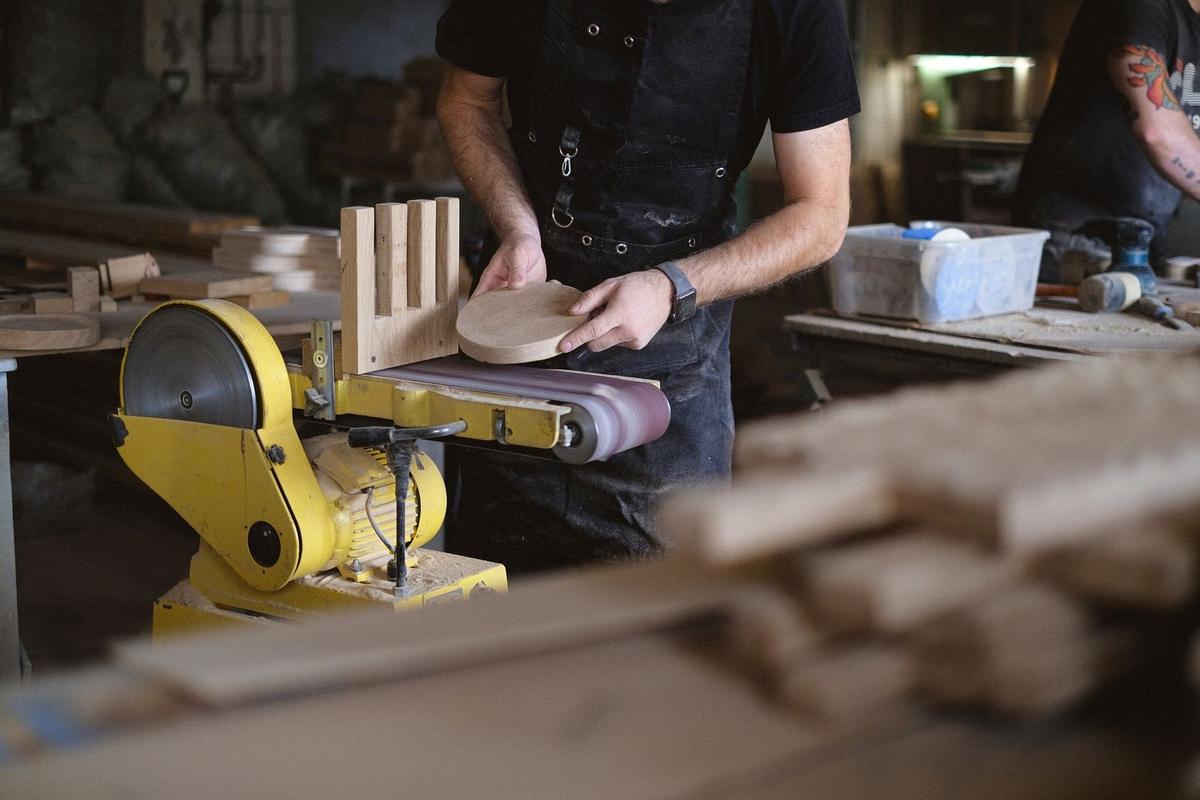 Homme ponçant du bois sur une machine dans un atelier de menuiserie Homme ponçant du bois sur une machine dans un atelier de menuiserie