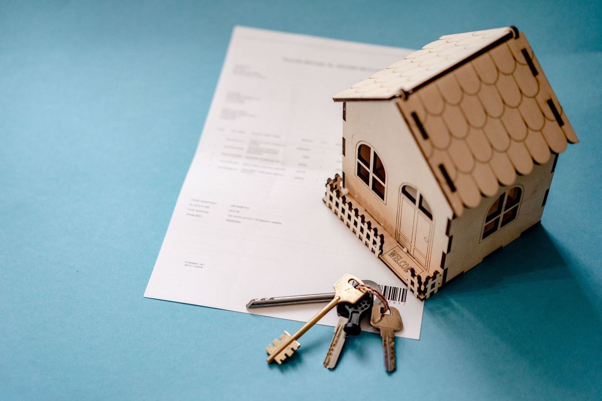 Maison en carton, clés et document sur fond bleu
