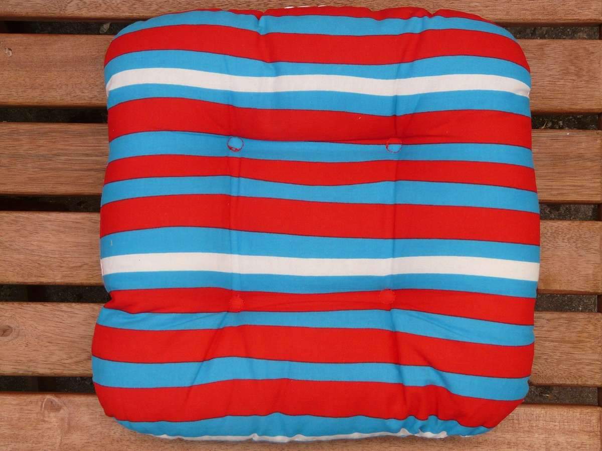 Coussin rayé rouge, bleu et blanc posé sur banc en bois